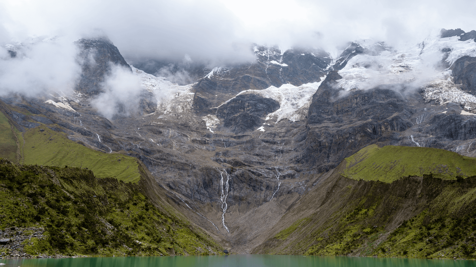 Serene mountain lake surrounded by misty peaks — mental clarity through sustainable travel 2025