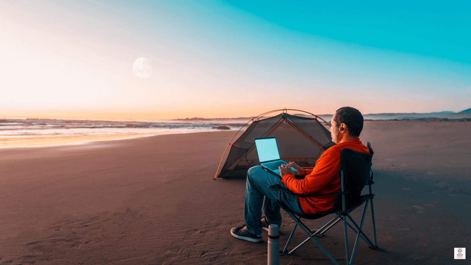 Digital nomad working on a laptop at sunset on a quiet beach, representing sustainable remote work in 2025.