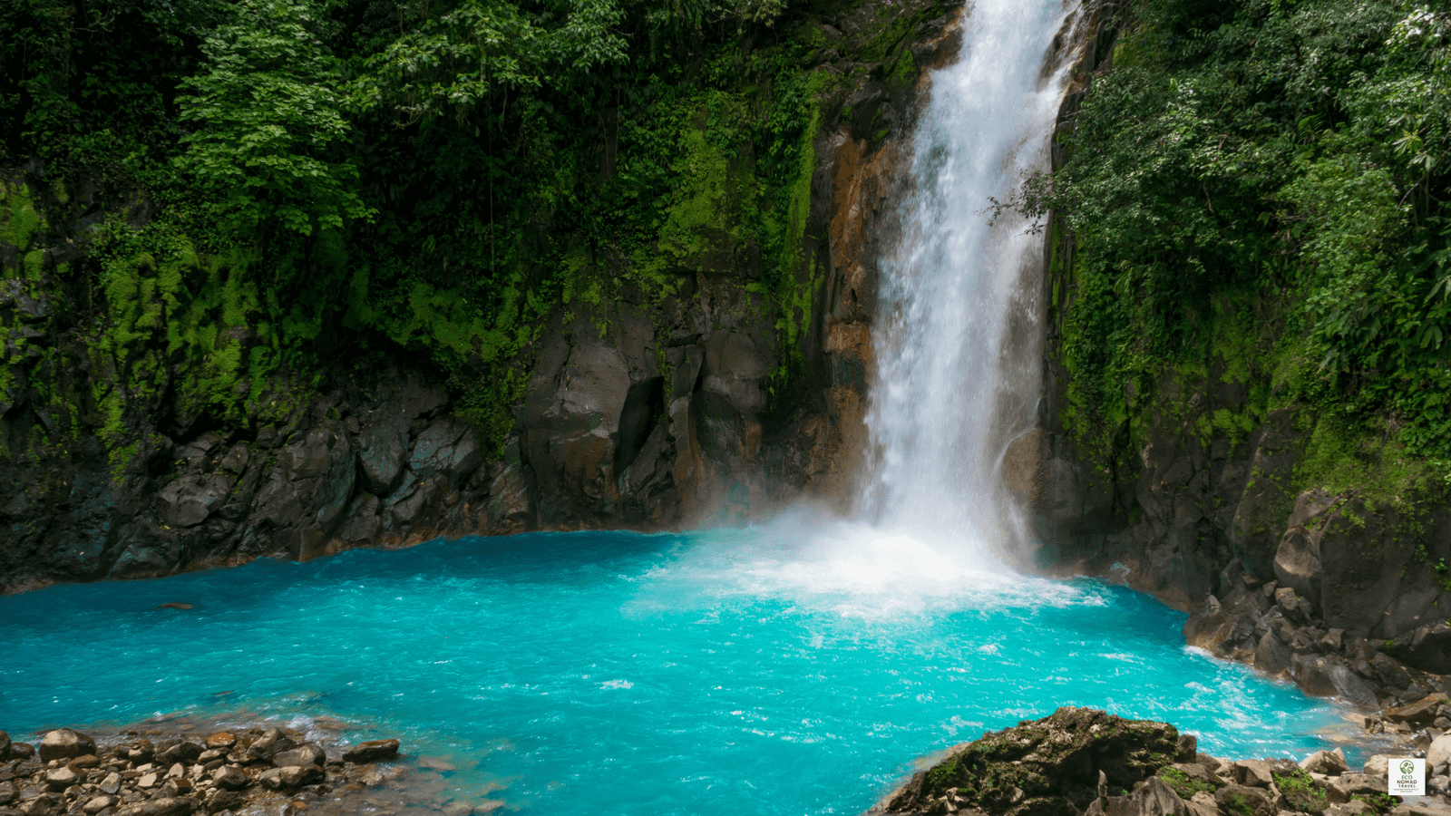 Rio Celeste waterfall in Costa Rica pouring into a blue pool, surrounded by rainforest near eco lodges and farm stays.