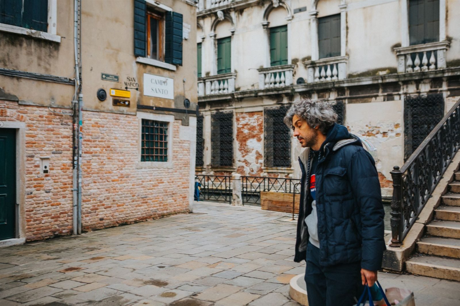 A traveller with a bag walking alone through a narrow old European street